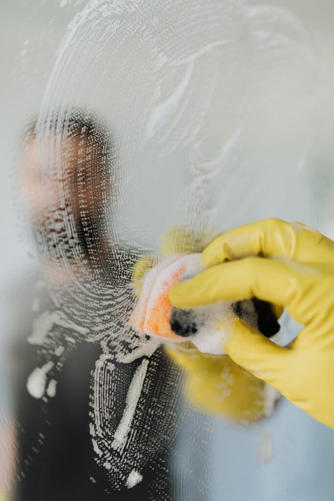 Anonymous man cleaning mirror in bathroom